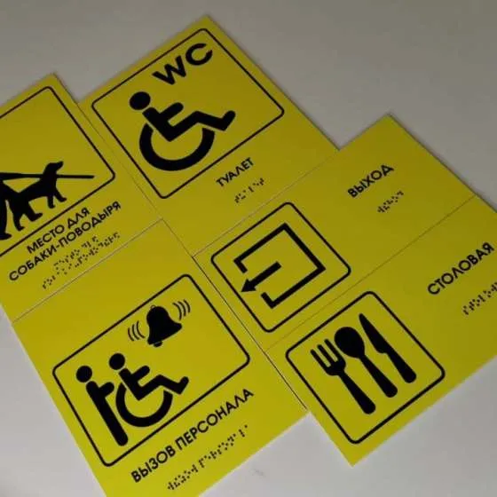 пример тактильных табличек с шрифтом Брайля — «Место для собаки поводыря», «Туалет», «Вызов персонала», «Выход», «Столовая»
